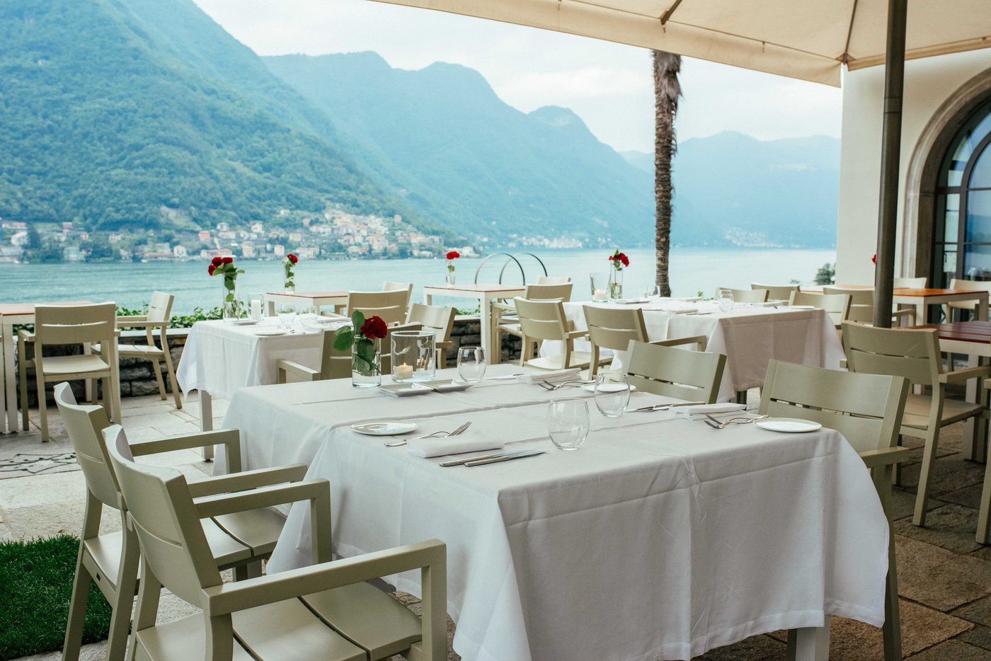 Terrazza elegante con tavoli apparecchiati direttamente sulle rive del Lago di Como